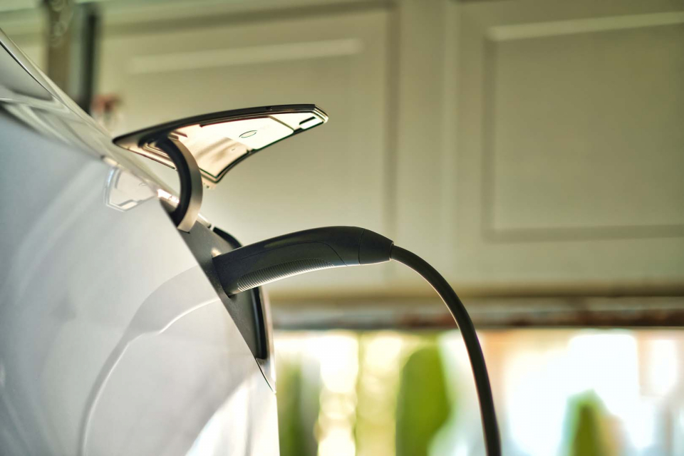 An EV charger plugged into an electric car that is parked inside a residential garage