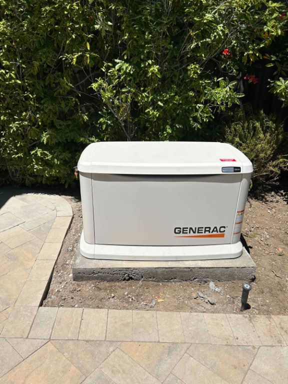 Generac generator installed on a slab of concrete behind a residential clients house